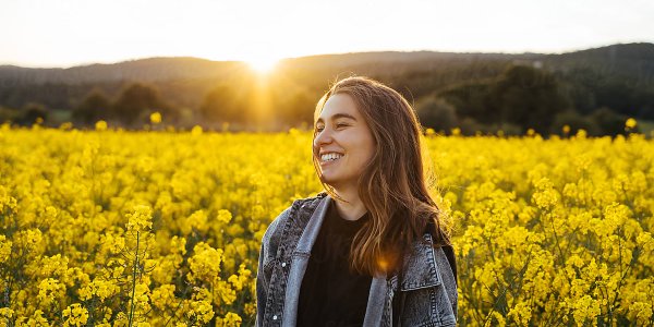 A women is smiling standing on a flower field